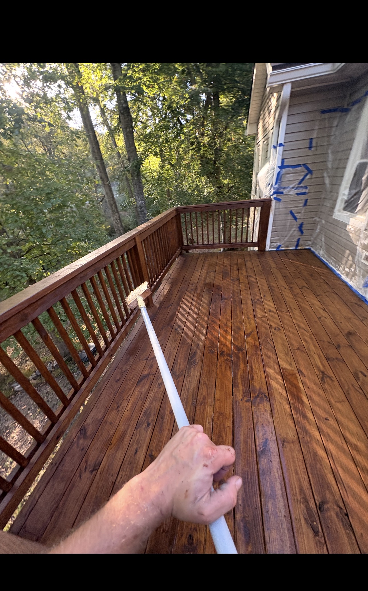 Mid-stain close-up of a deck being refreshed with new finish