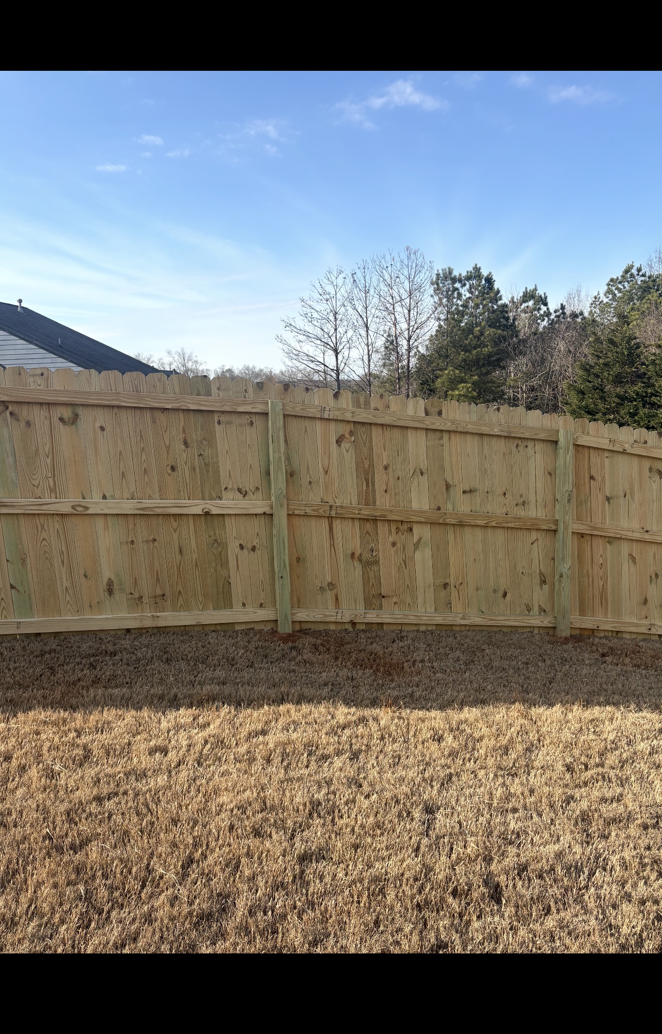 Painter staining a light brown deck mid-job, edge freshly coated